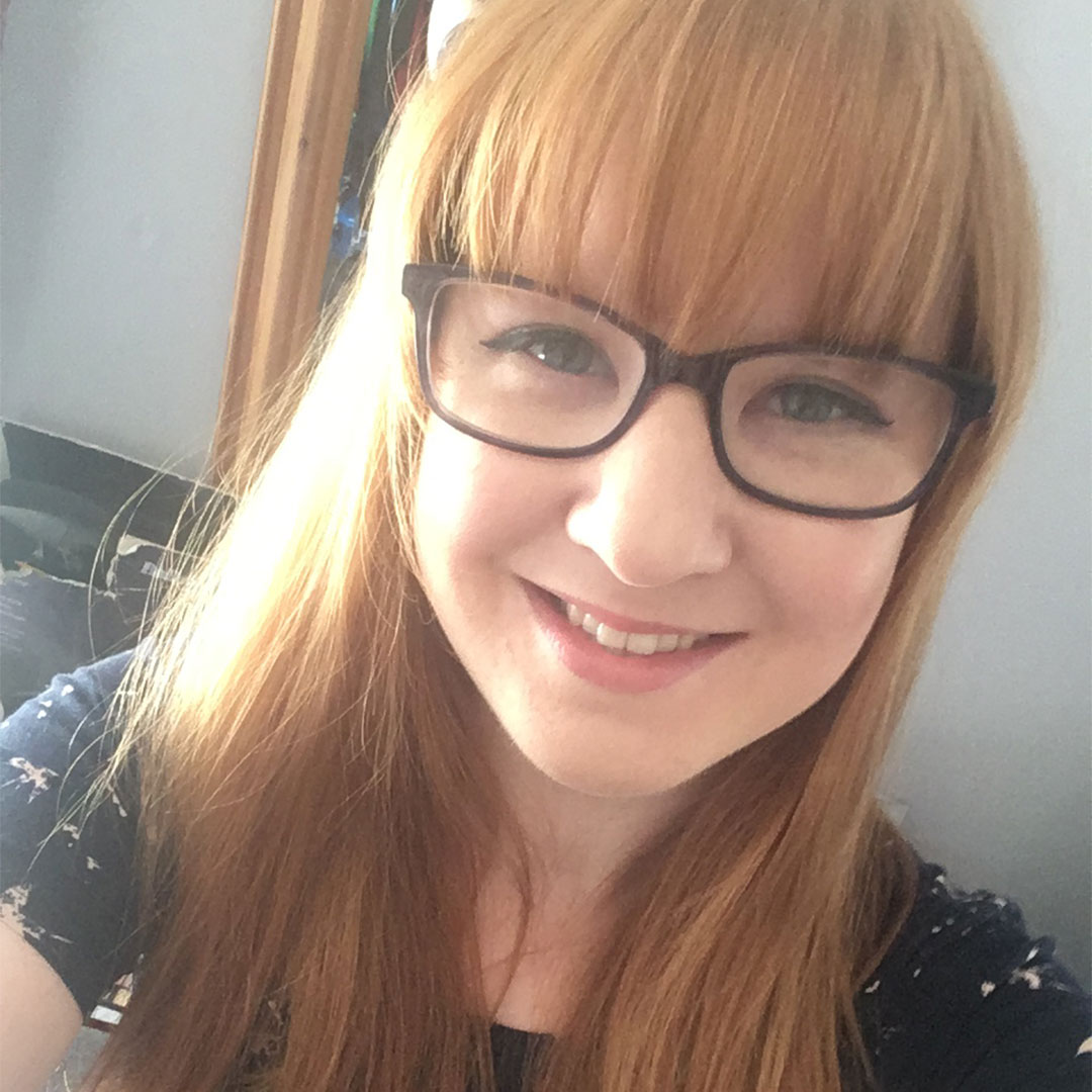 A photo of a woman with glasses smiling at the camera