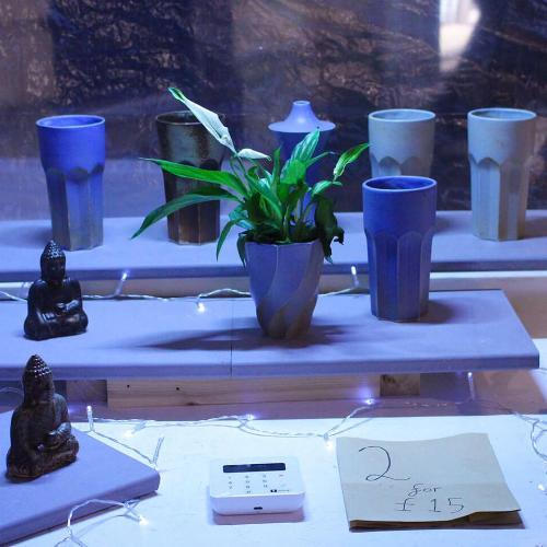 market stall showing a variety of ceramic goods, models, pot plants, and cups