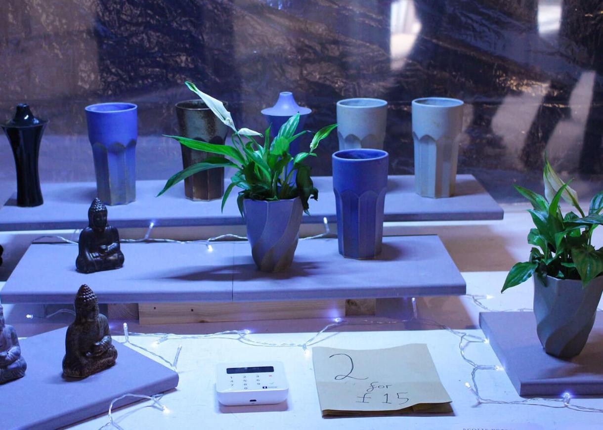 market stall showing a variety of ceramic goods, models, pot plants, and cups