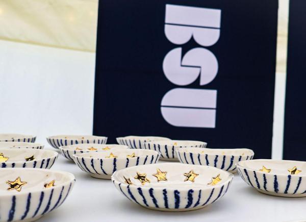 decorated ceramic bowls lined up on table with BSU banner behind.