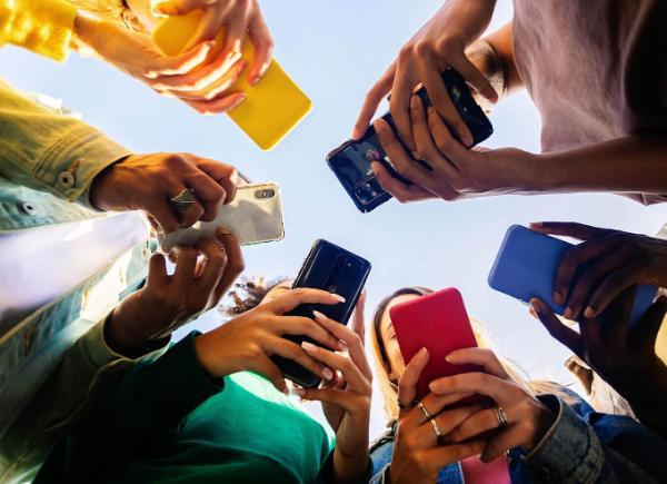 A number of people holding mobile phones in a circle