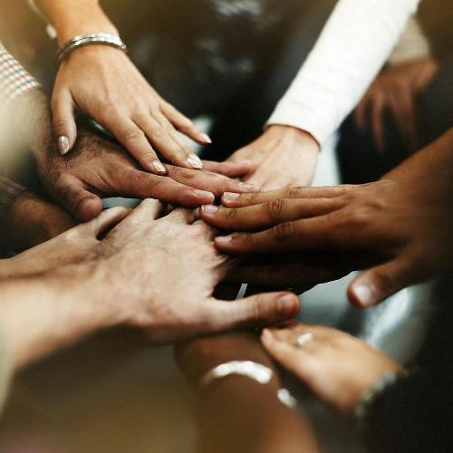 a close up photo of people putting their hands into a pile, symbolising agreement.