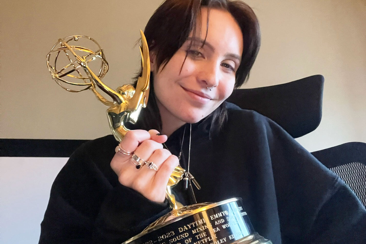 Person smiling and holding an Emmy award