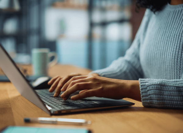 A woman sits at her desk typing on her laptop