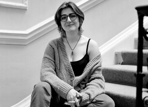 A black and white image of a person sat on a flight of stairs