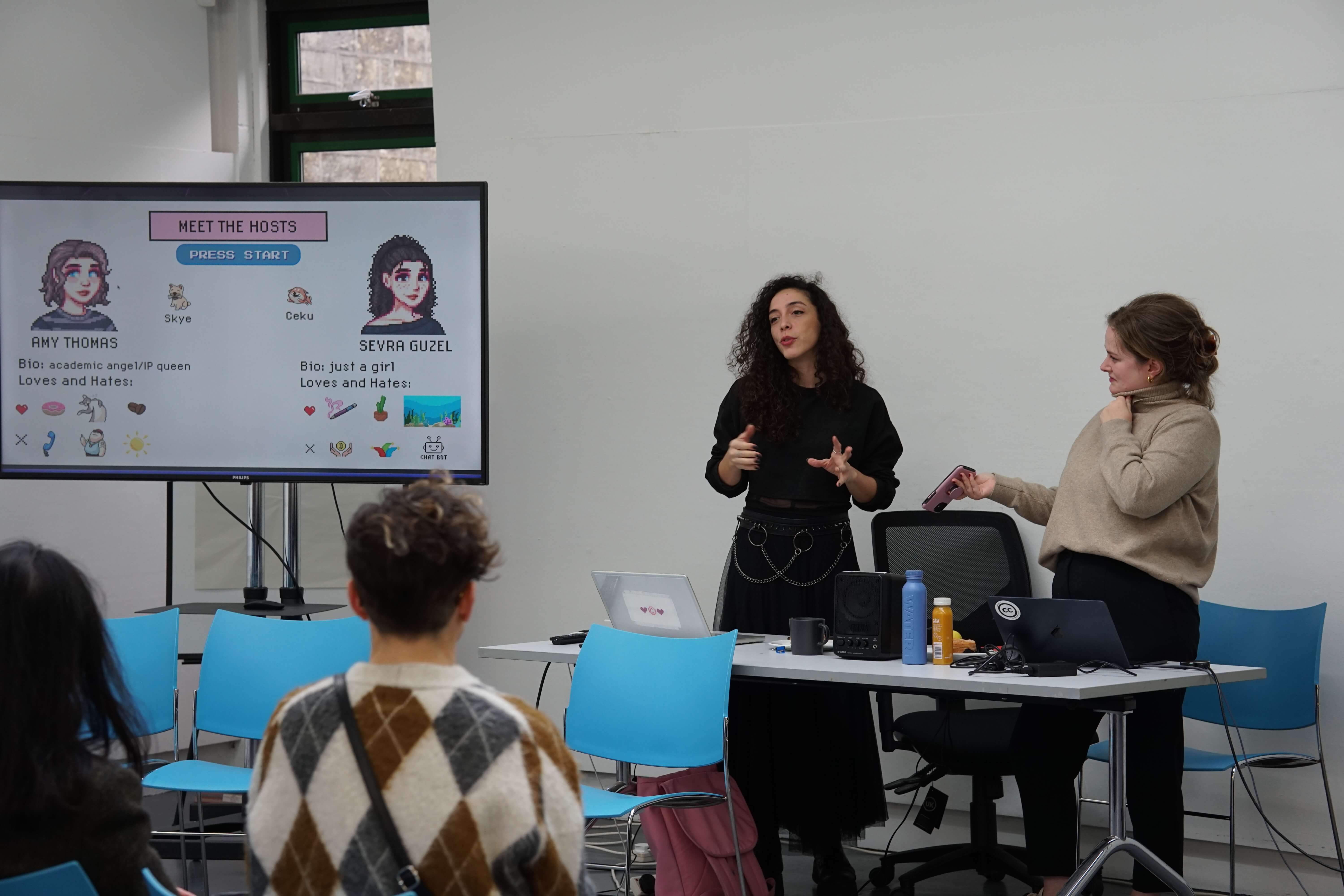 Two women stood in front of a screen giving a talk to a room full of people