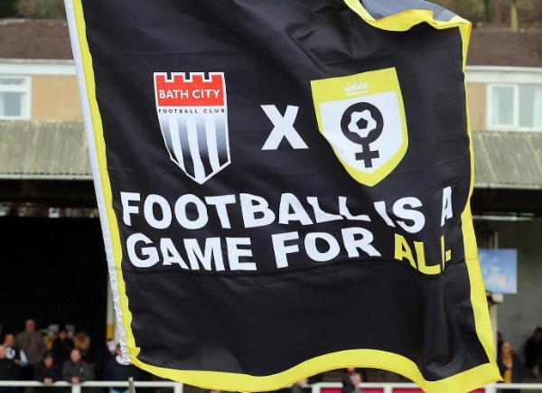 A flag showing the Bath City and Her Game Too badges with the words Football is a game for all written on it