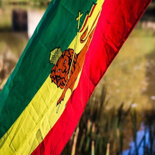 The Ethiopian flag waving in front of a lake in the sunshine