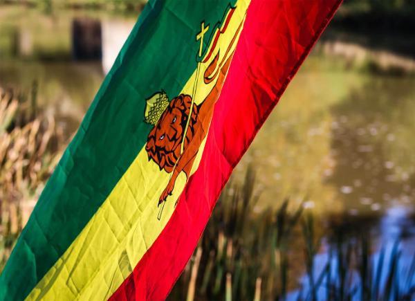 The Ethiopian flag waving in front of a lake in the sunshine