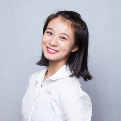 Person in white shirt with shoulder-length black hair smiling at camera