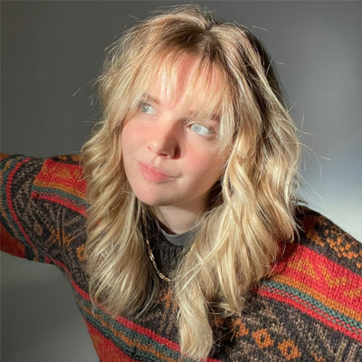 Person with long blonde hair in red patterned jumper