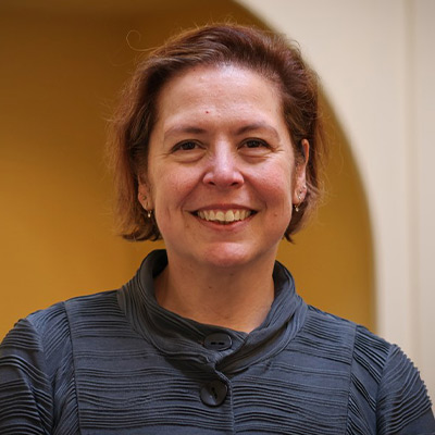 Person in blue top with short dark hair smiling