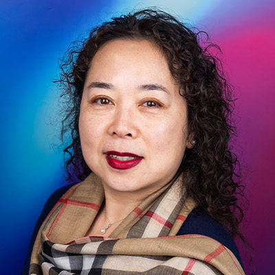 Headshot of someone with long curly dark hair in Burberry style scarf