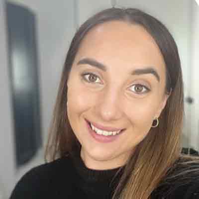 Person with long dark hair smiling at camera