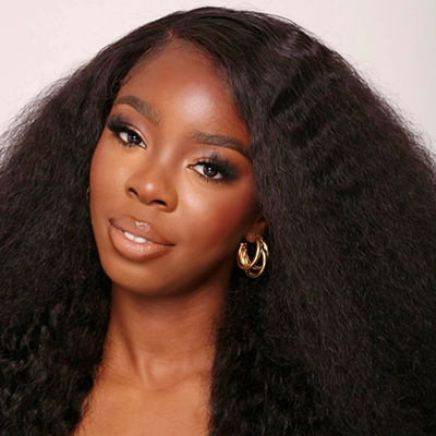 A person with long, dark hair and gold hoop earrings looks at the camera