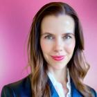 A person wearing smart business attire stands in front of a bright pink background