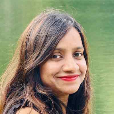 Person with long dark hair and red lipstick smiling