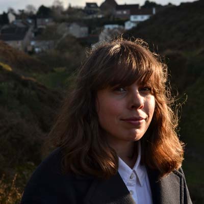 Person with long brown hair standing in a valley