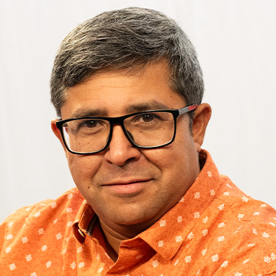 Person with glasses and short dark hair in orange shirt