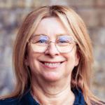 Smiling woman wearing gold rimmed hexagonal glasses