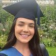 A person smiling at the camera while wearing BSU graduation robes