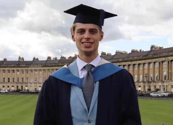 A student wearing Bath Spa University graduation robes stands outside the Royal Crescent