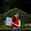 A person with long brown hair holds her dissertation up to the camera