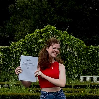 A person with long brown hair holds her dissertation up to the camera