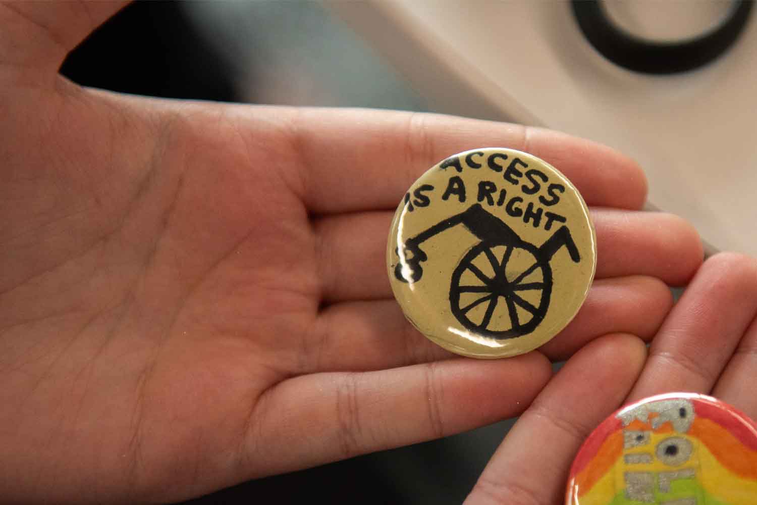 Hands holding home-made badges saying access is a right