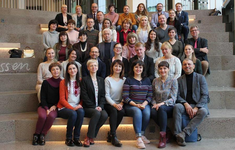 A large group of academics sit on the steps for a group photo