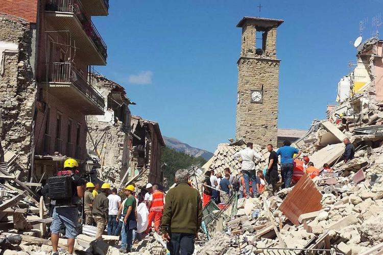 People walk amongst the rubble and remains of buildings after a major earthquake in a town.