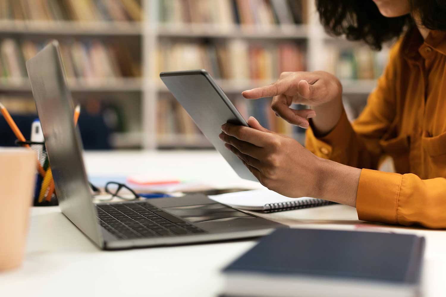 A person sitting in the library uses a touch-screen device