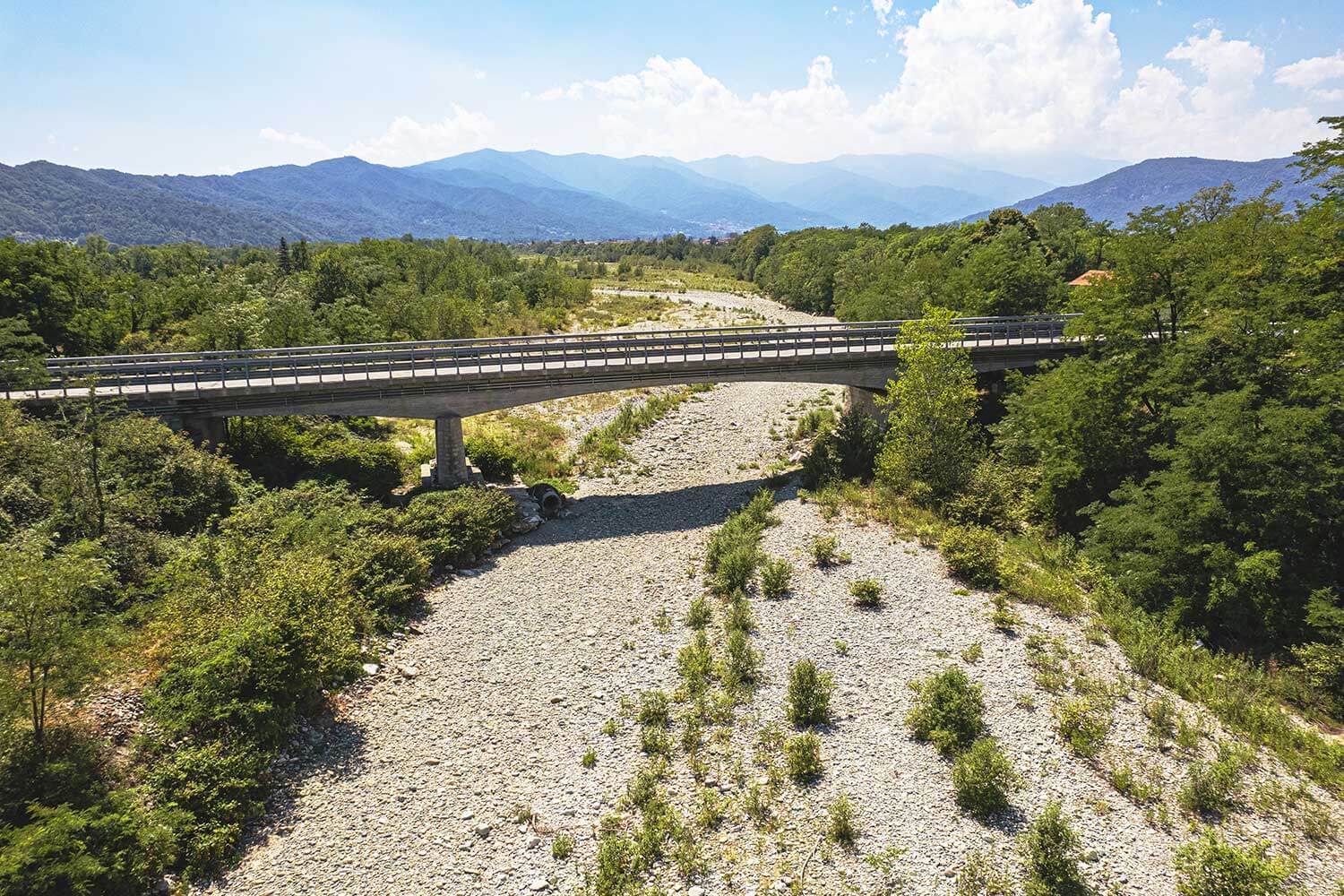 A dry riverbed due to prolonged drought. A bridge crosses over the riverbed.