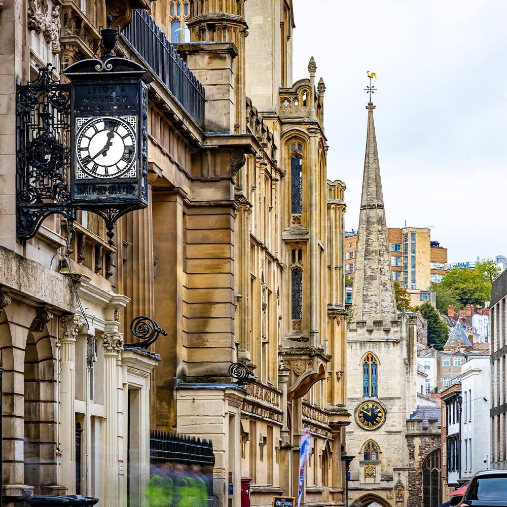 View up medieval Bristol street with clocks and spires
