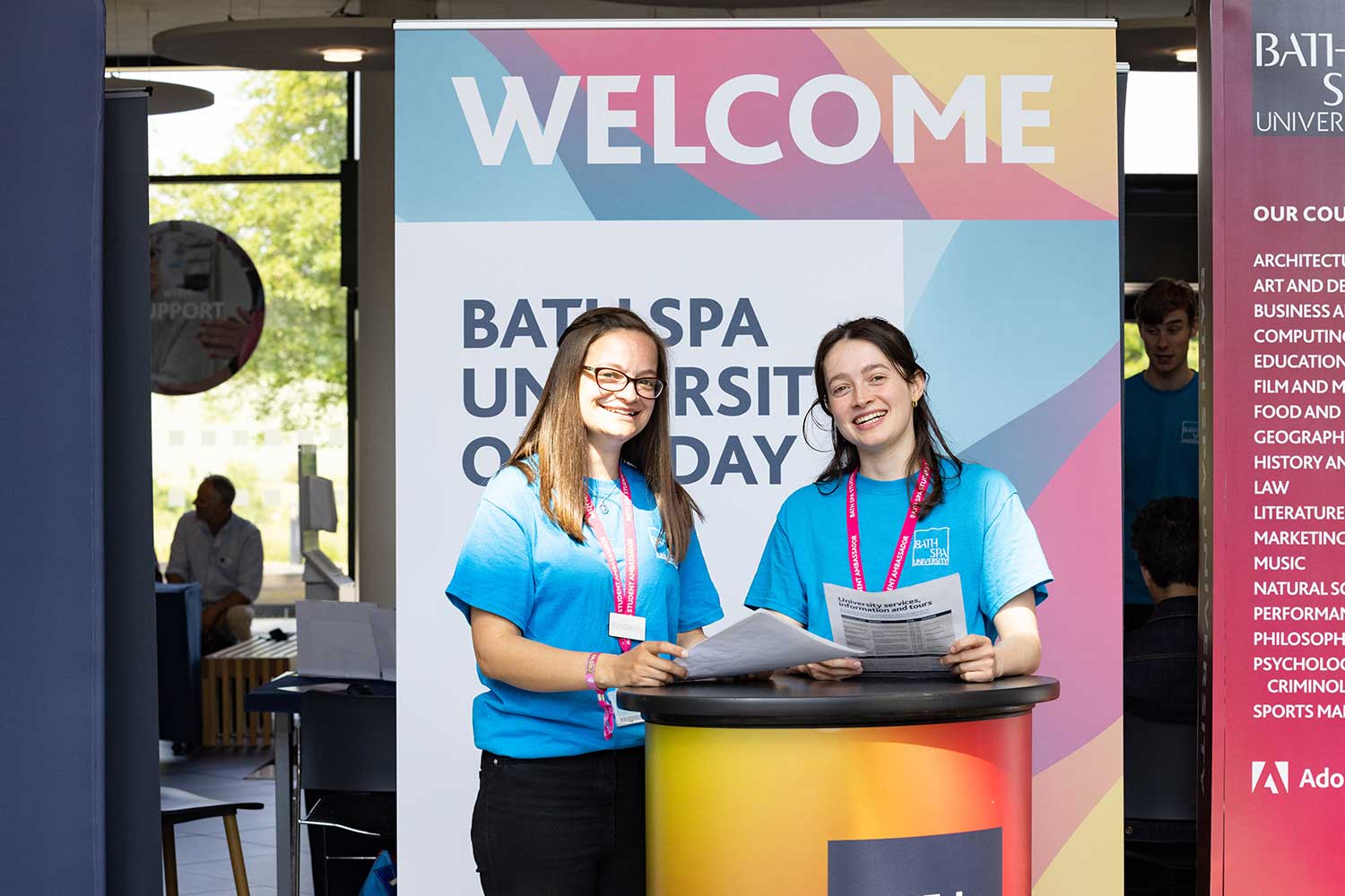 Two Student Ambassadors stand in the Commons Atrium to greet guests