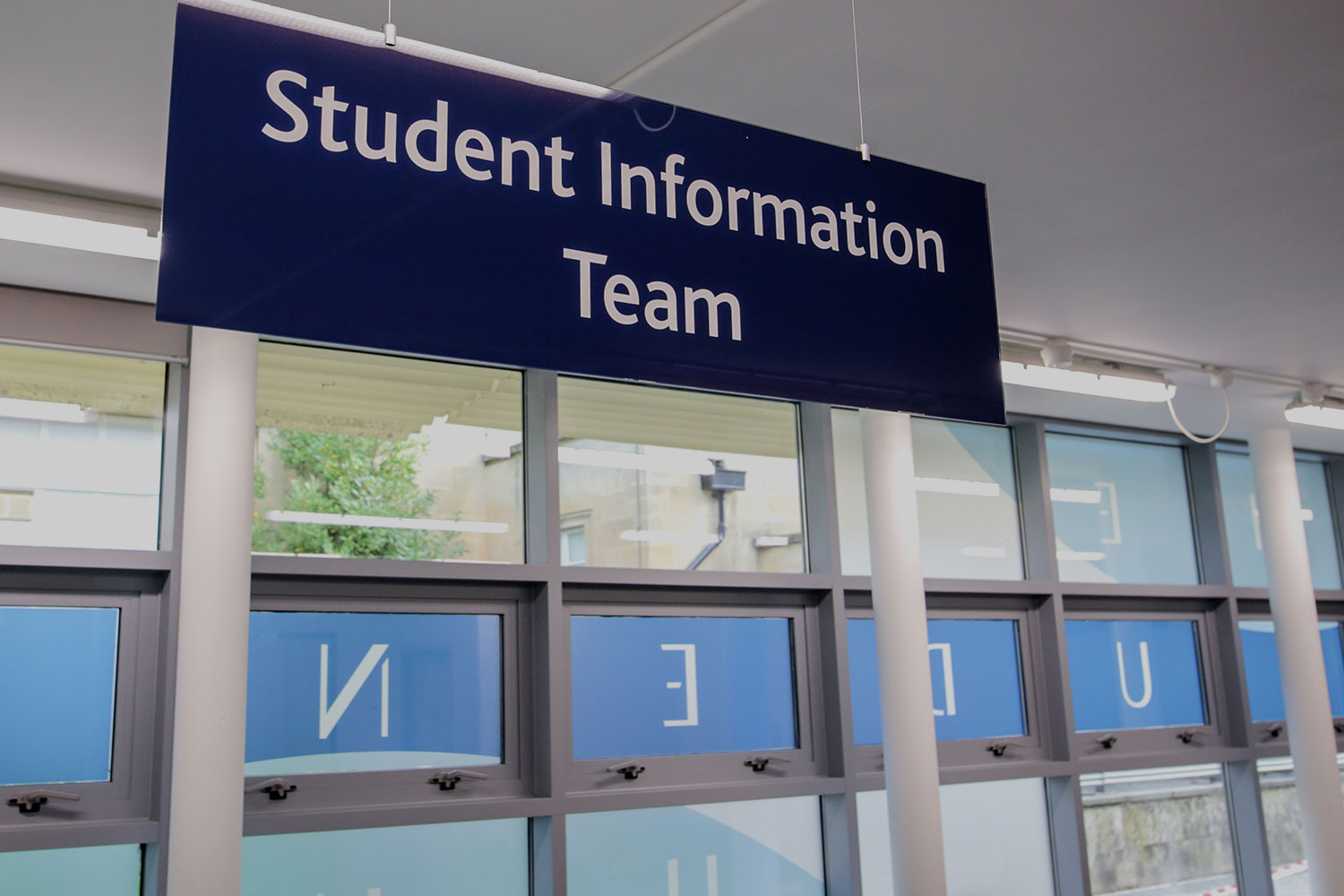 Large sign for Student Information Team hanging above a desk, with windows in the background