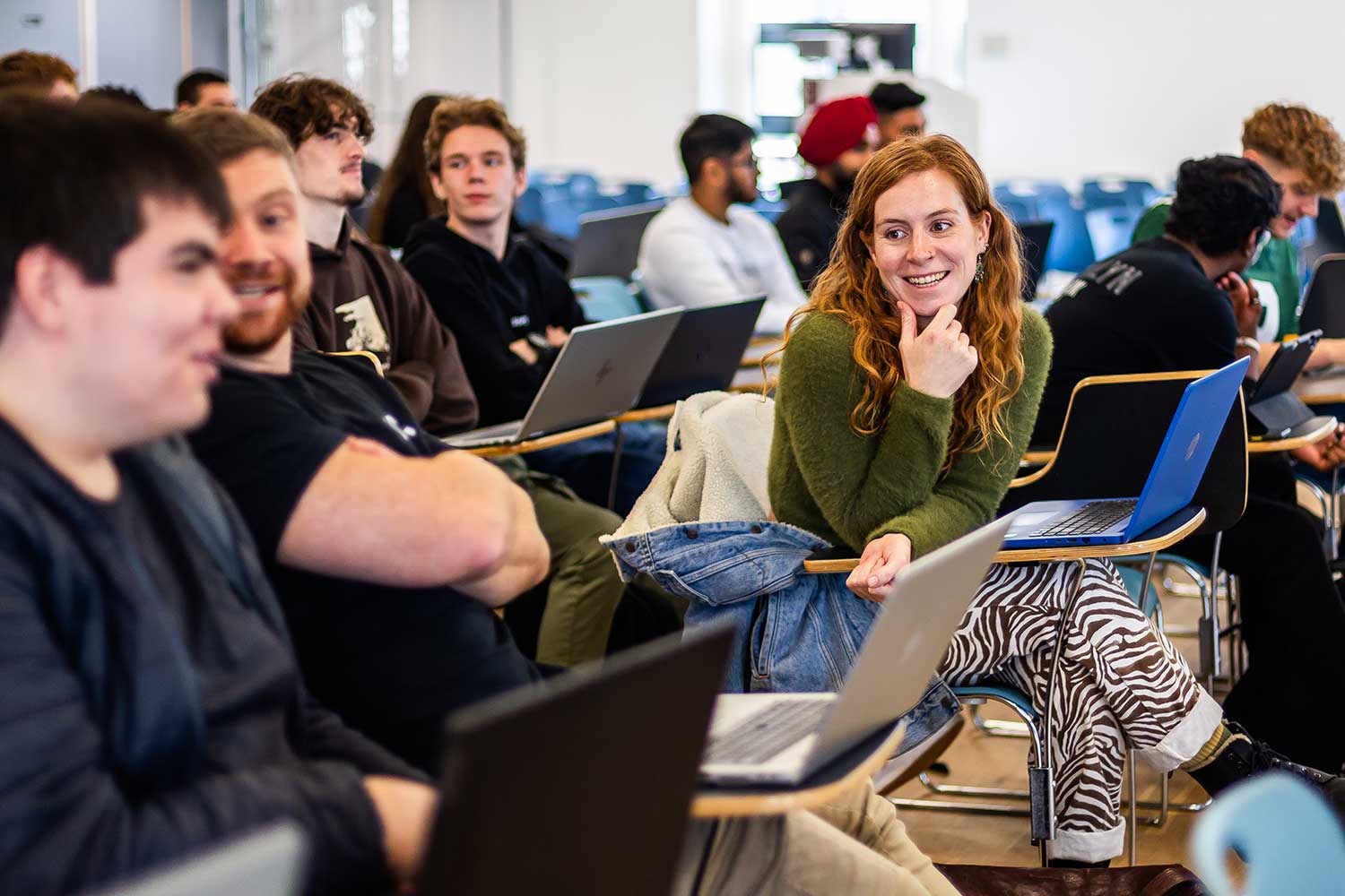 Students sitting in a lecture hall chat before the lecture begins