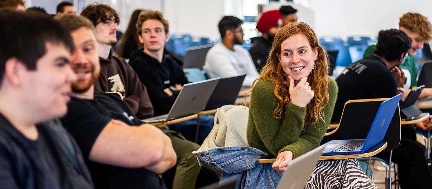 Students sitting in a lecture hall chat before the lecture begins