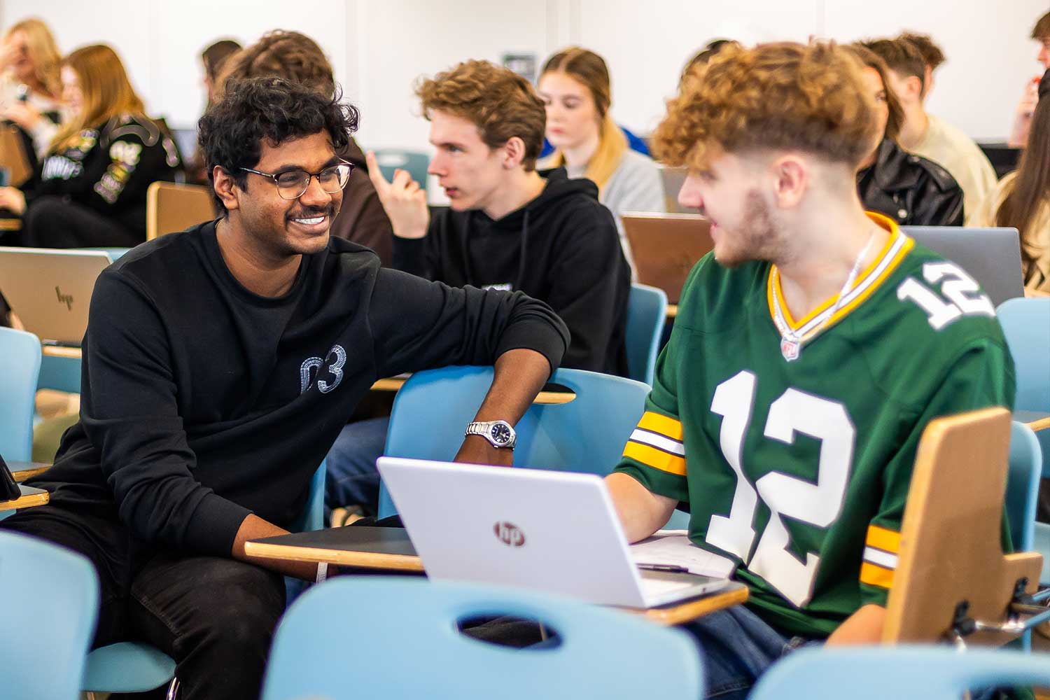 Two students turn to each other to talk during a lecture