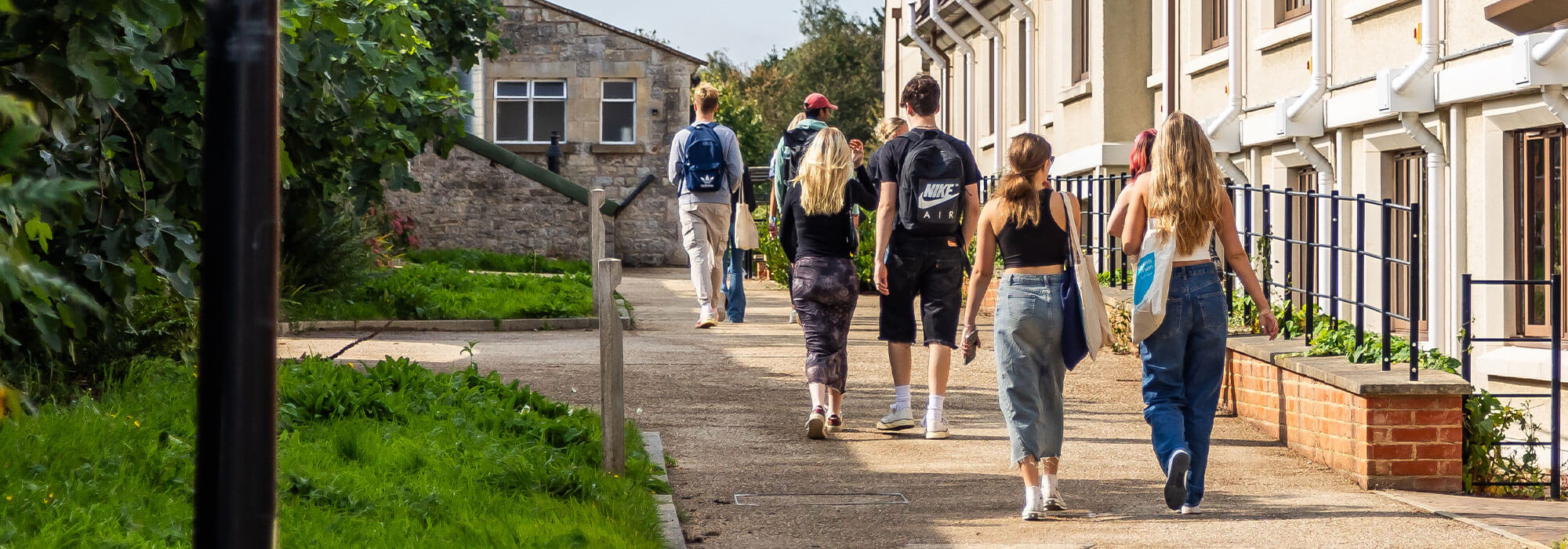Students with their back to the camera walking near the exterior of their university accommodation