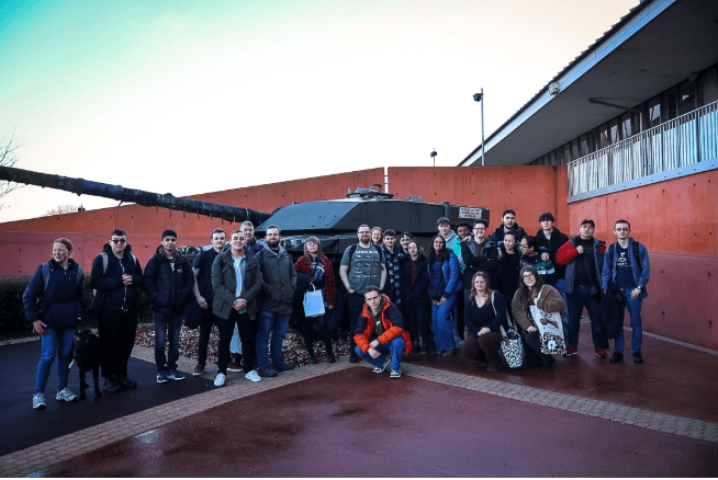 A large group of students and staff stood outside the Tank Museum.